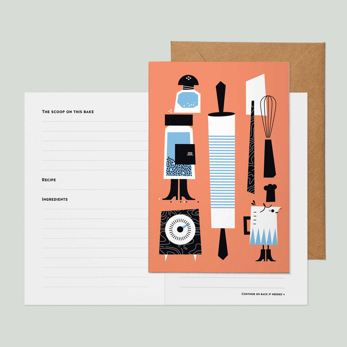 A recipe card greeting card featuring a salmon pink front cover illustrated with kitchen utensils and tools in black, white, and light blue, shown with a brown kraft envelope and a white lined recipe insert page on a light gray background.