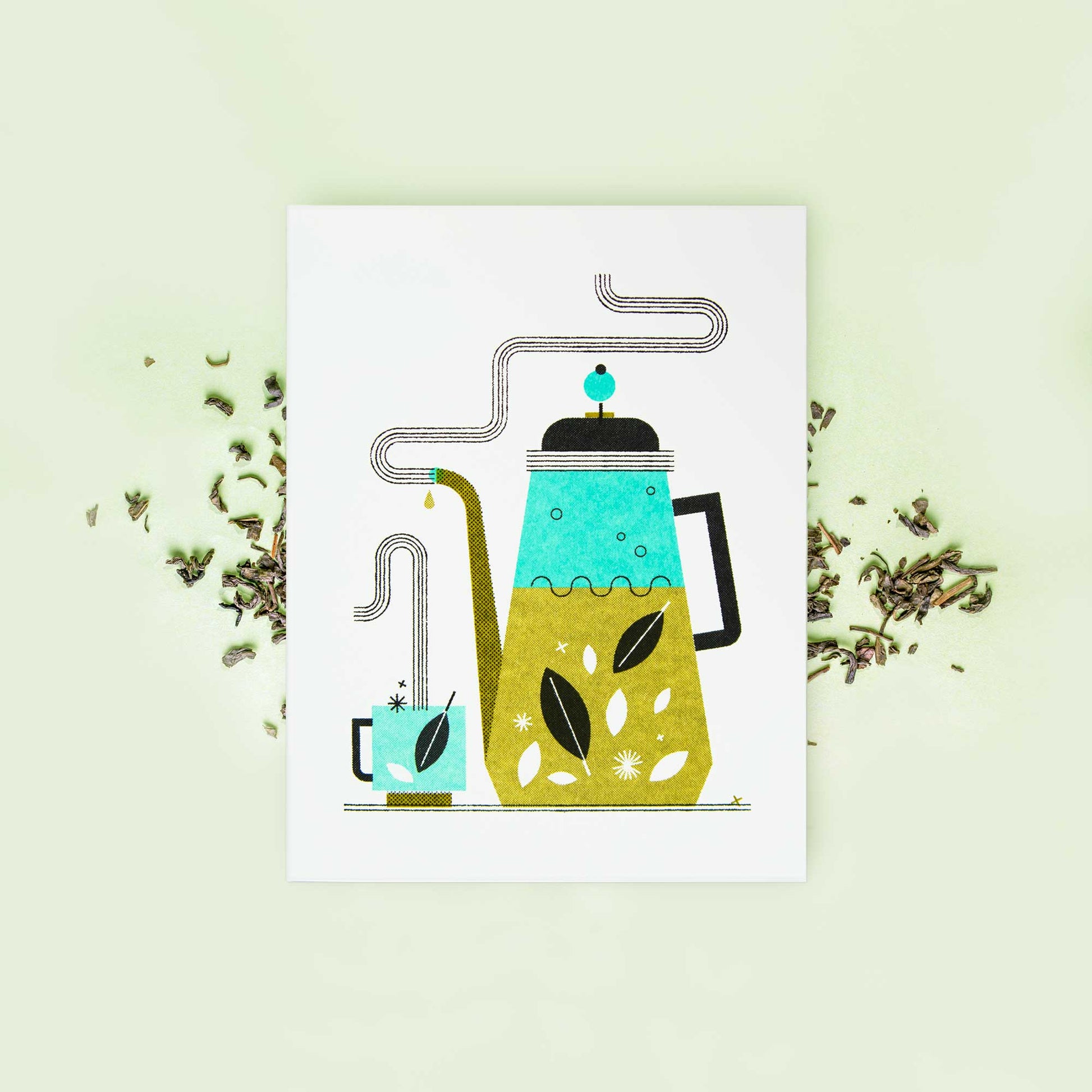 A greeting card featuring a stylized illustration of a teapot and cup with tea leaves, displayed on a light green background with scattered loose tea leaves.