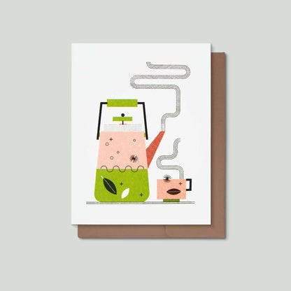 A greeting card featuring a stylized illustration of a pink teapot and cup with green and orange accents, shown with a brown envelope on a light gray background.