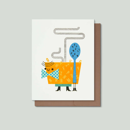 A greeting card with a whimsical illustration of a bowl of alphabet soup character wearing a blue polka-dot bow tie and standing next to a blue spoon with the words get well soon on it, shown with a brown envelope on a light gray background.
