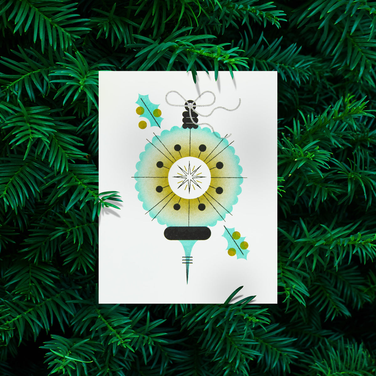 A  greeting card featuring a stylized, minimalist Christmas ornament and holly leaves, displayed against a background of green pine needles.