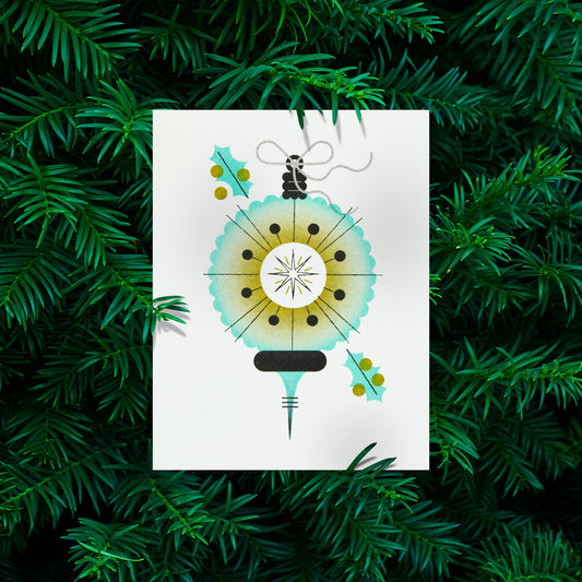 A  greeting card featuring a stylized, minimalist Christmas ornament and holly leaves, displayed against a background of green pine needles.