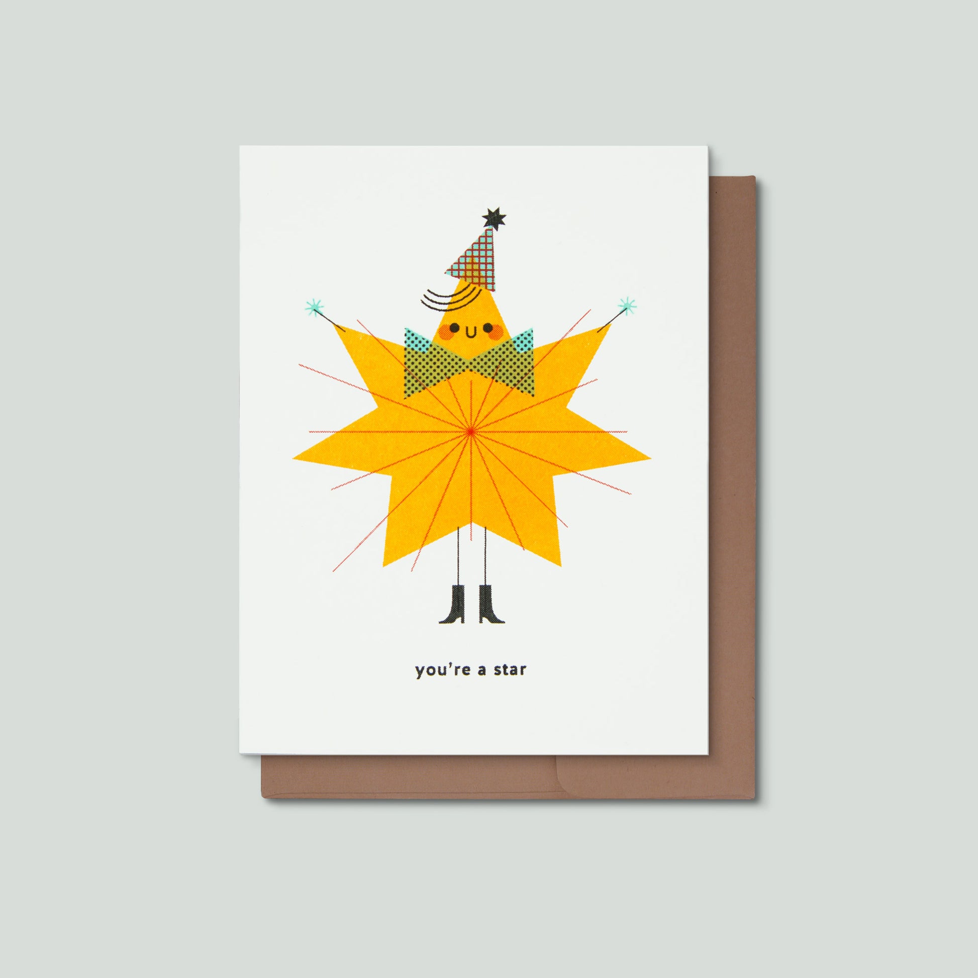 A greeting card with a whimsical illustration of a star-shaped character wearing a party hat and bow tie, with the text 'you're a star' below, shown with a brown envelope on a light gray background.