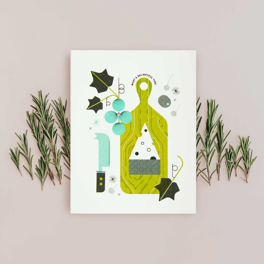 An illustrated greeting card featuring a stylized illustration of a green cutting board, grapes, leaves, and cheese, displayed on beige background with sprigs of rosemary