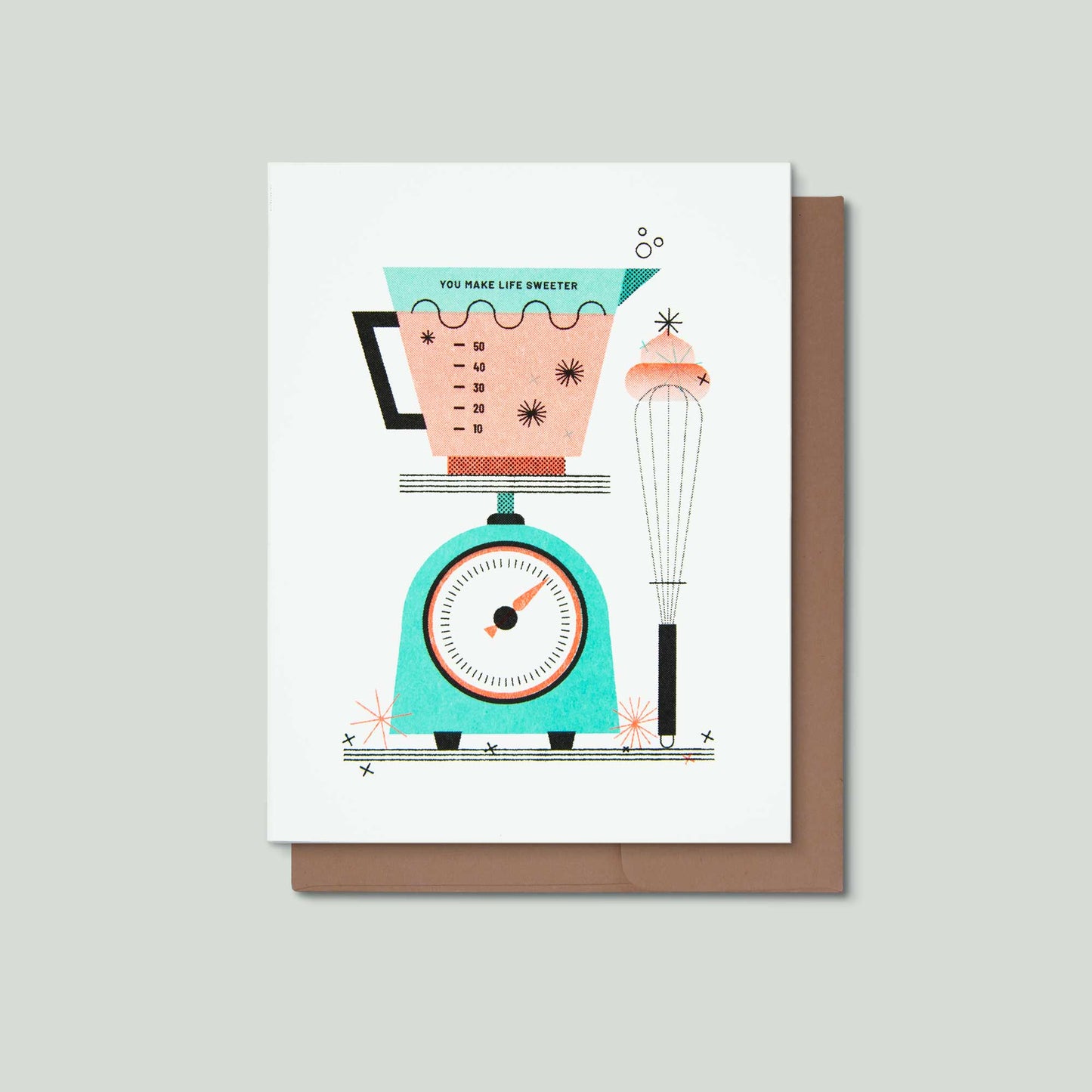 A greeting card with a retro-style illustration of a turquoise kitchen scale, measuring cup, and whisk, with the text 'YOU MAKE LIFE SWEETER', shown with a brown envelope on a light gray background.