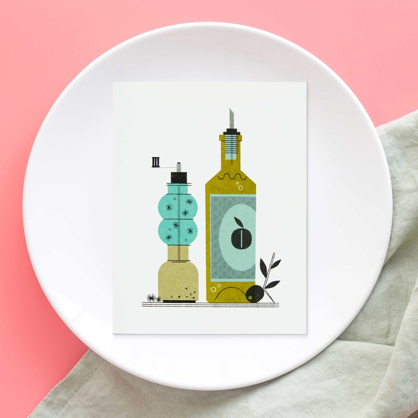 A risograph greeting card featuring a stylized illustration of olive oil & pepper bottles, one turquoise and one olive green, displayed on a white ceramic plate against a pink background with a light beige cloth.
