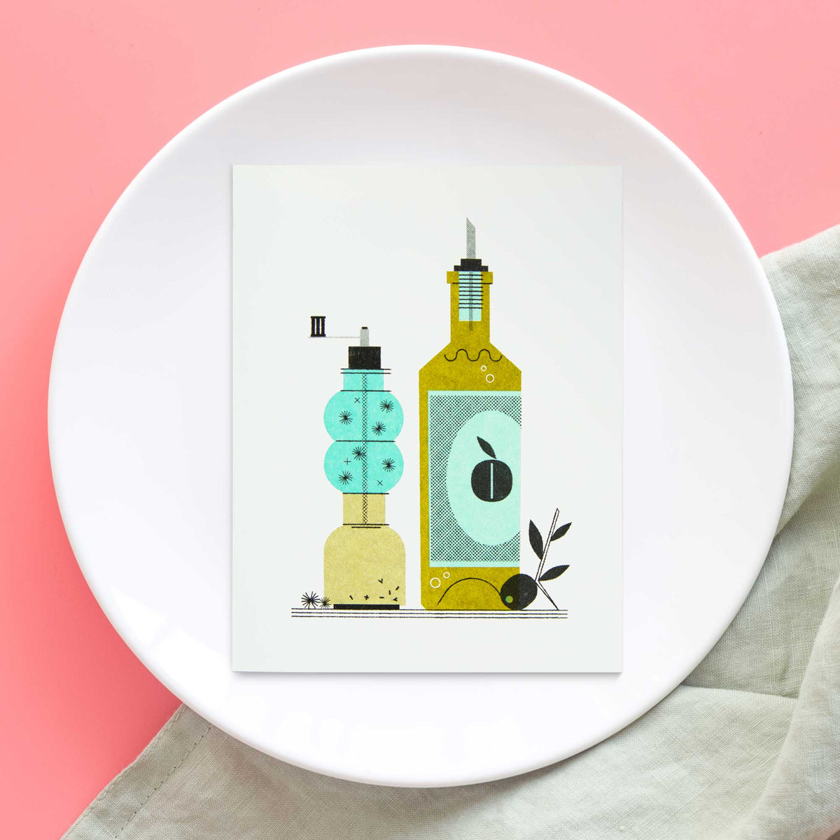 A risograph greeting card featuring a stylized illustration of olive oil & pepper bottles, one turquoise and one olive green, displayed on a white ceramic plate against a pink background with a light beige cloth.