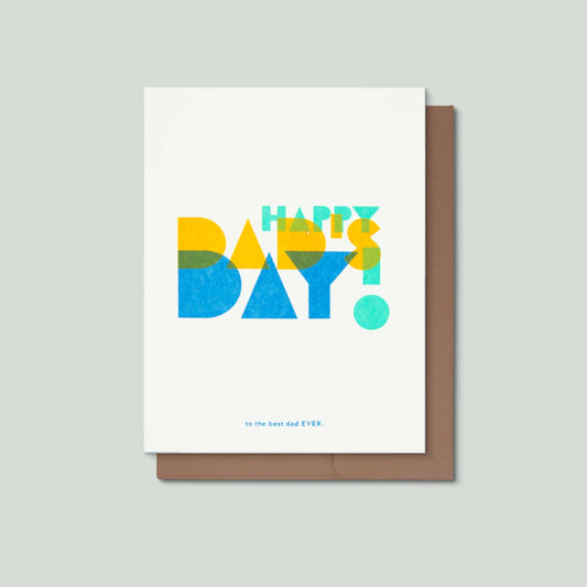 A risograph card with a white front and a brown envelope behind it, printed with the words “HAPPY DAD's DAY!” in large colorful geometric letters and small blue text reading “to the best dad EVER.”.